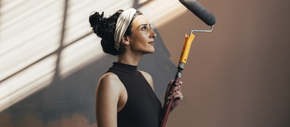 Happy female person standing and holding painting roller