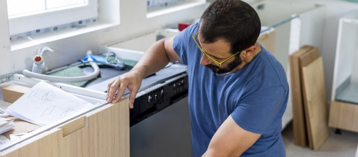 Mature man  installing furniture in domestic kitchen